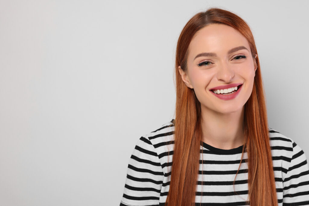 Smiling young woman in a striped shirt representing confidence, health, and empowerment as part of women’s health Lorain County support programs.