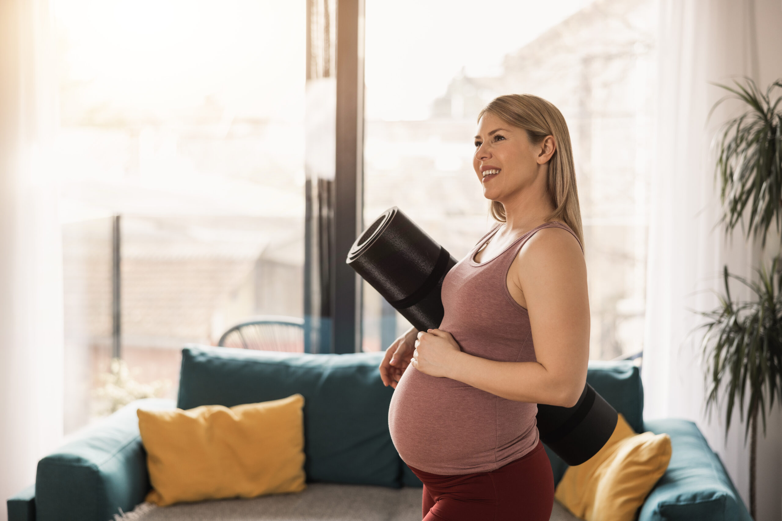 Pregnant woman holding exercise mat is ready for practice yoga at home in the morning.